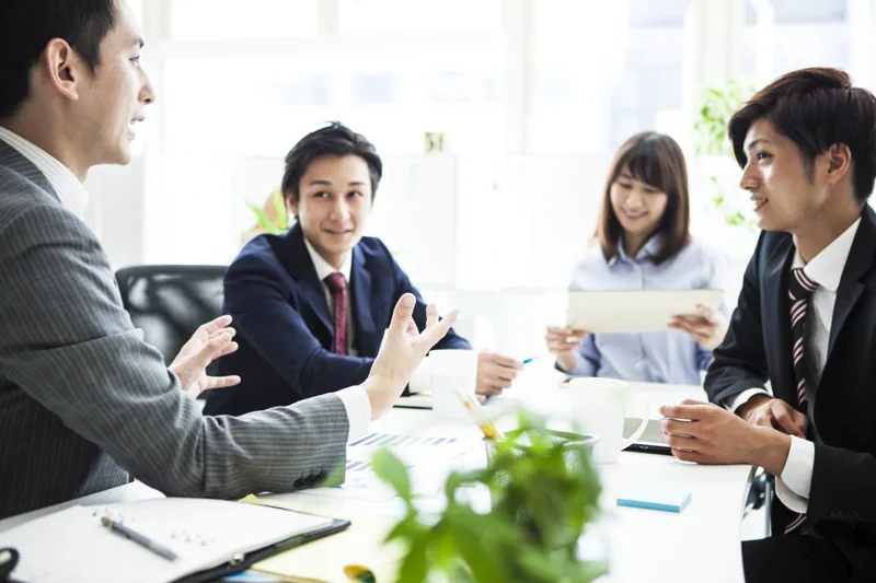 会議室で向かい合って話し合う4人の社員